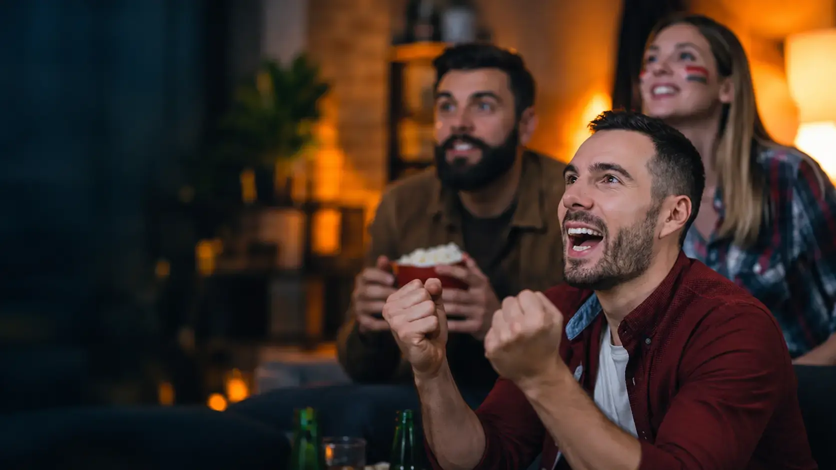 Friends cheering while watching live sport together at home